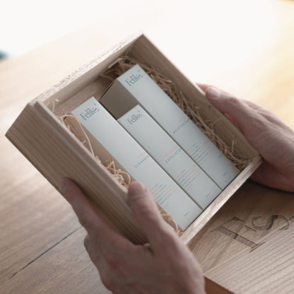 The image shows the Feliks skincare gift box held in a man's hands. The gift box is wooden. Inside the gift box are three boxes of mens skincare including cleanser, exfoliator and moisturiser.